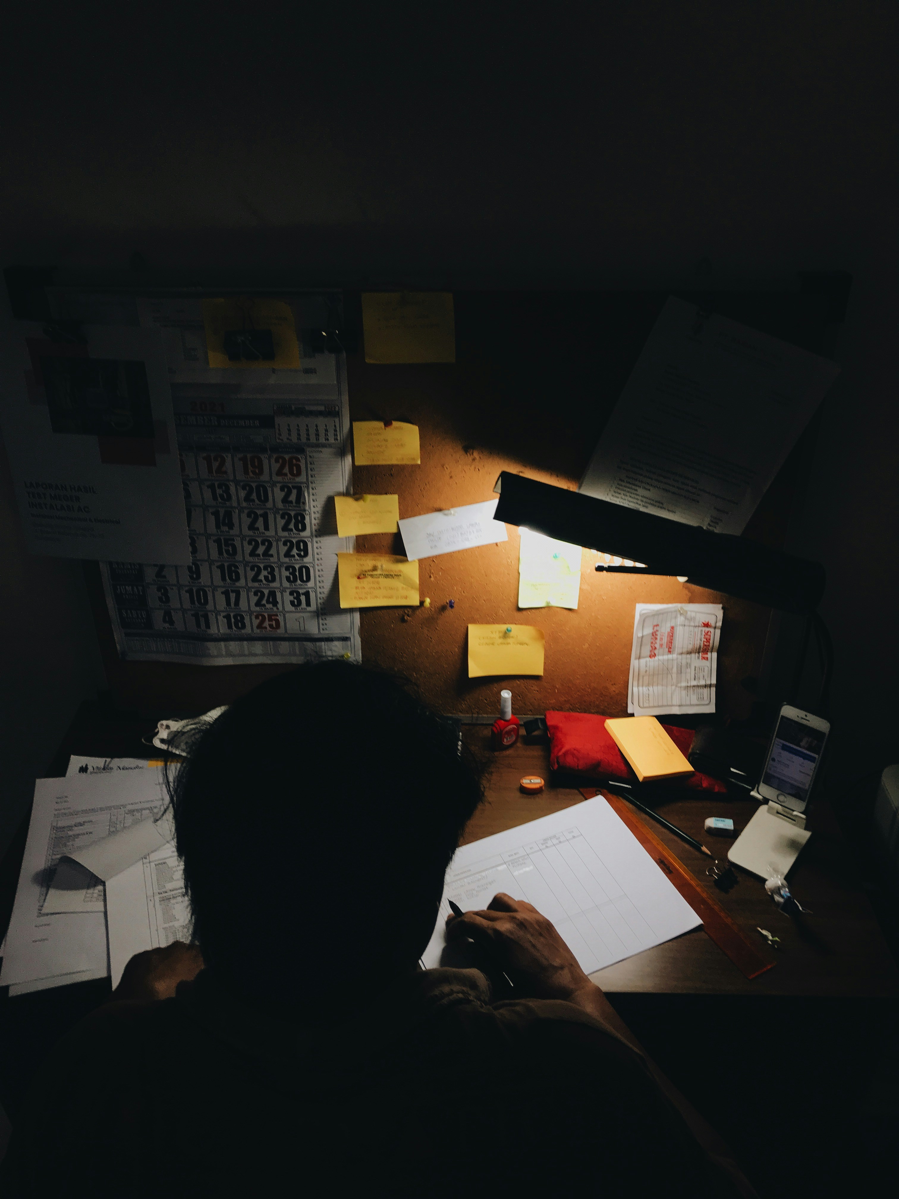 Chaotic workspace with scattered papers, sticky notes, and late-night work